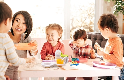 Eine Frau sitzt mit vier Kindern beim Frühstück