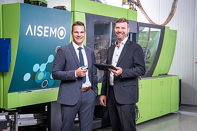 Die Geschäftsführer Wolfgang Auer (links) und Werner Schwarz an einer Spritzgießmaschine, die mit AISEMO Analytics ausgestattet ist 