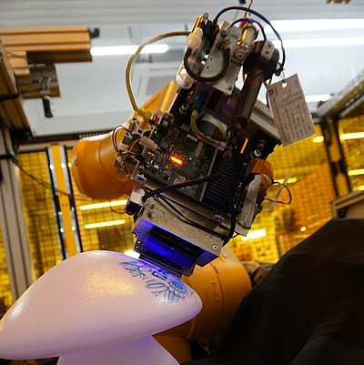 Die RoboInkjet-Druckanlage bedruckt konformal ein 3D-Spritzgussteil